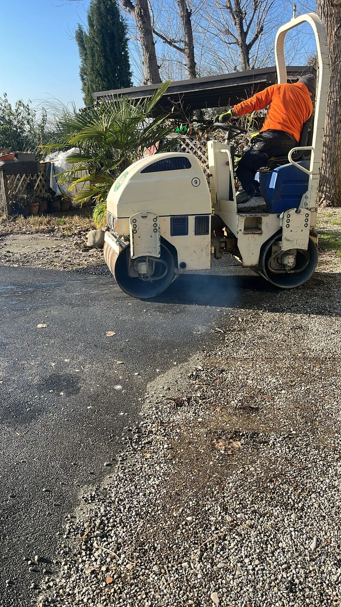 Operaio alla guida di un rullo compattatore su asfalto fresco